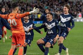 Goalie Paul Izzo is swamped by Victory teammates after his penalty shootout heroics against City. (Will Murray/AAP PHOTOS)